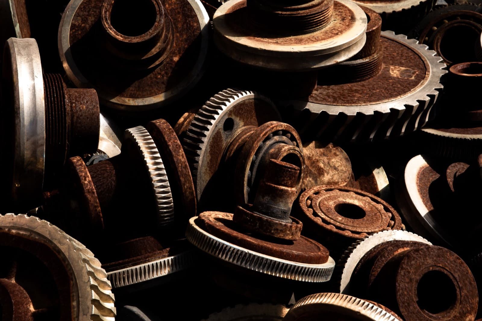 Pile of rusted, worn industrial gears and bearings — the aging mechanical components behind repeat elevator breakdowns