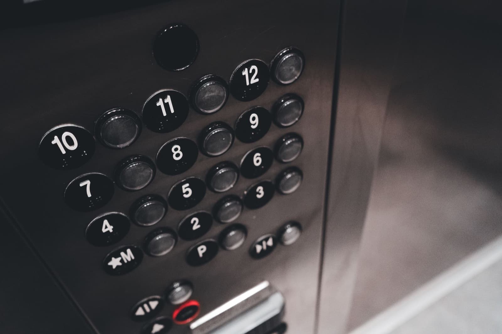 Metal elevator control panel with numbered buttons — in-car equipment governed by elevator code requirements
