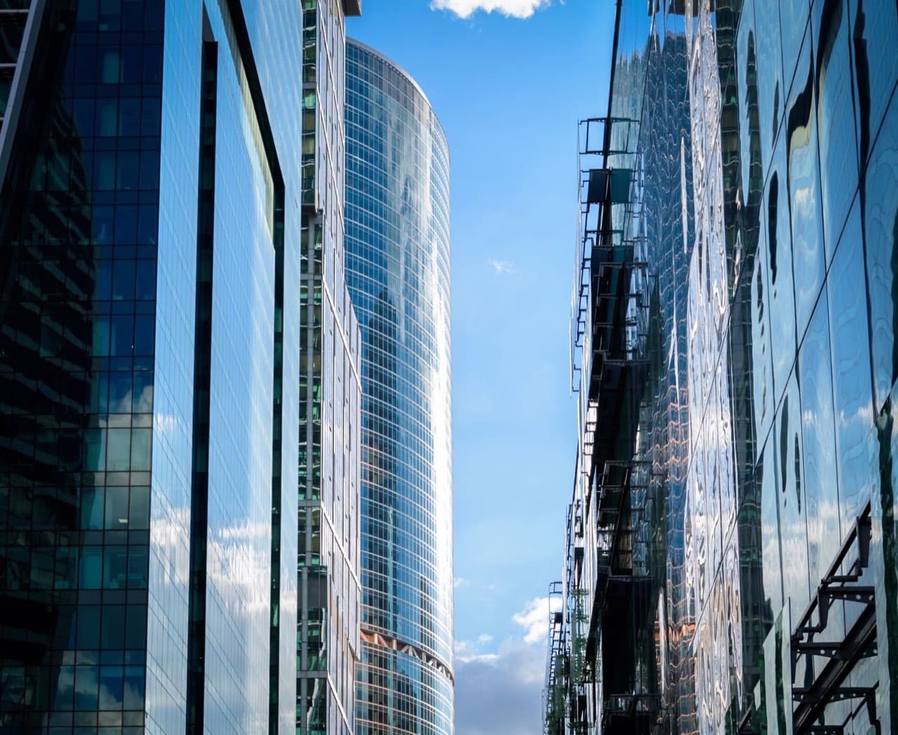 Glass high-rise buildings reflecting the sky — elevator due diligence before a building sale or acquisition