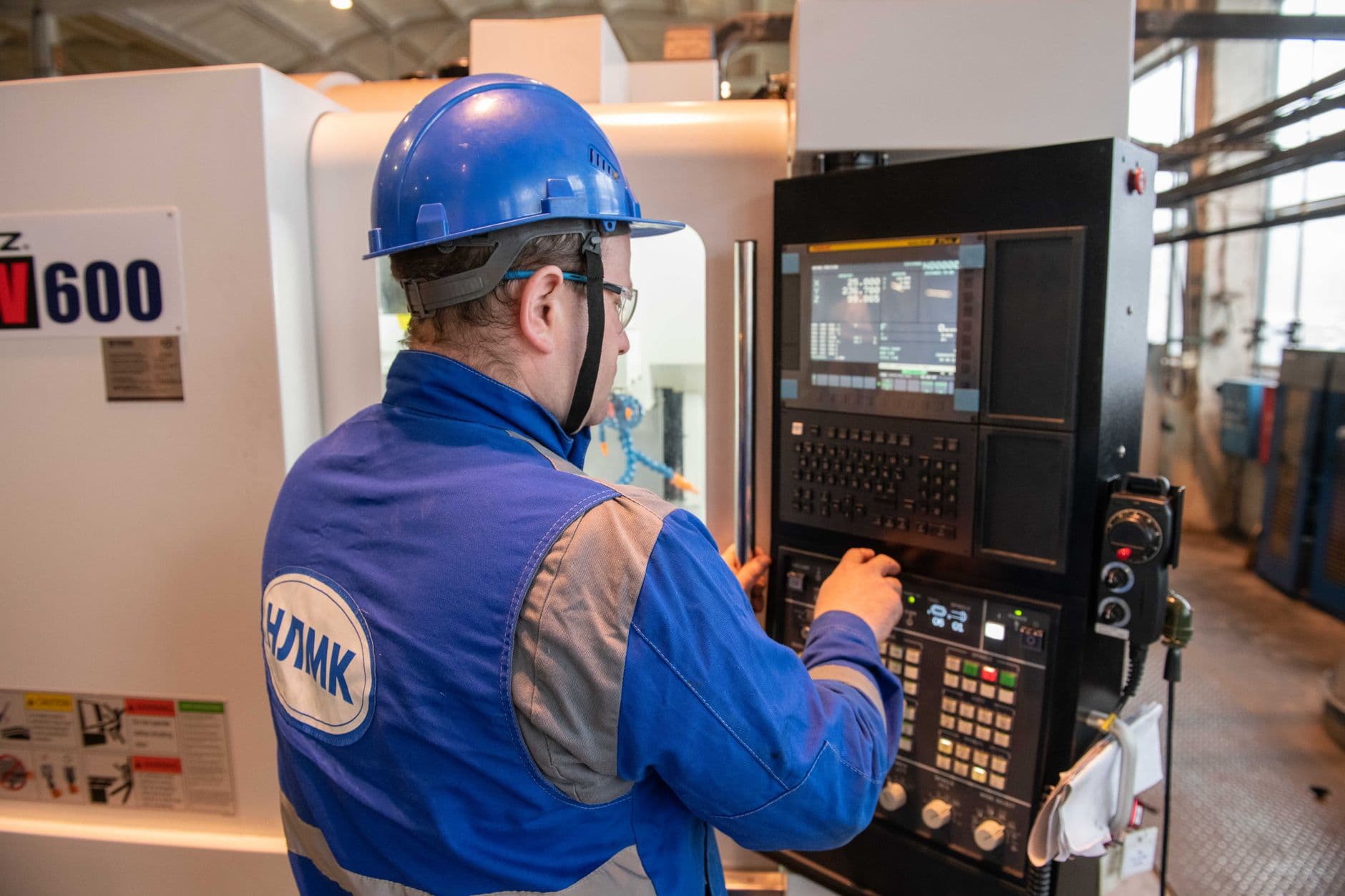 Elevator technician in work uniform servicing industrial machinery in a machine room