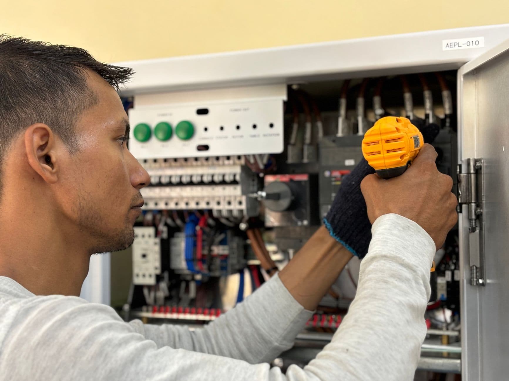 Elevator technician examining an open elevator controller panel with wiring visible